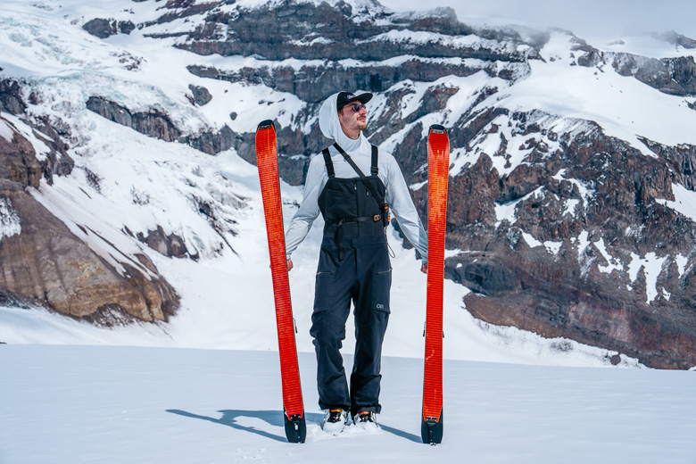 Men's ski bibs (standing with skis in front of glacier)