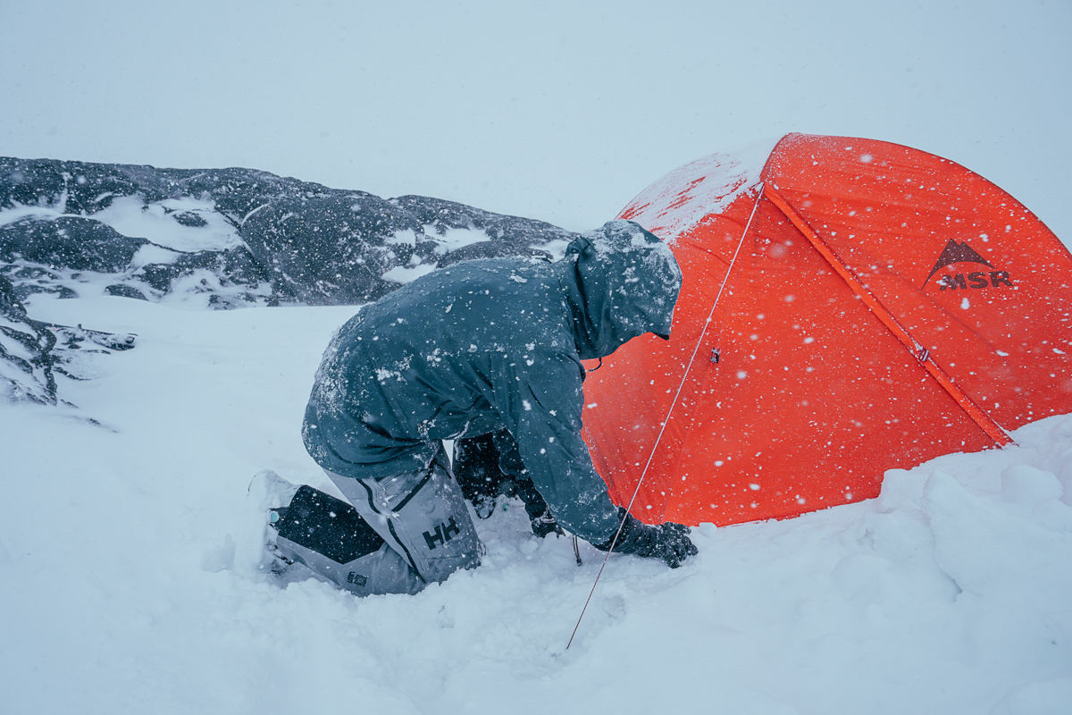 Ski bibs (kneeling in snow before tent)