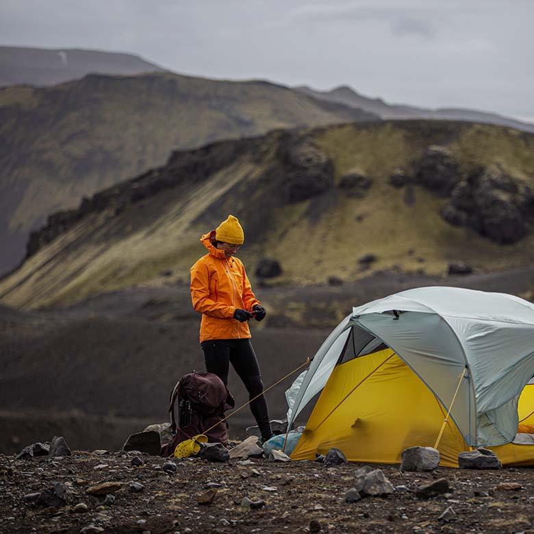 Hardshell vs. softshell jackets (standing next to tent in mountains)